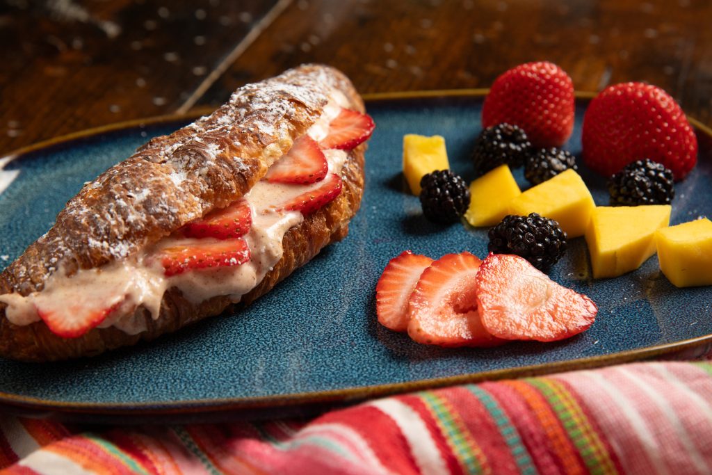 Plate with strawberry croissant and fresh fruit.