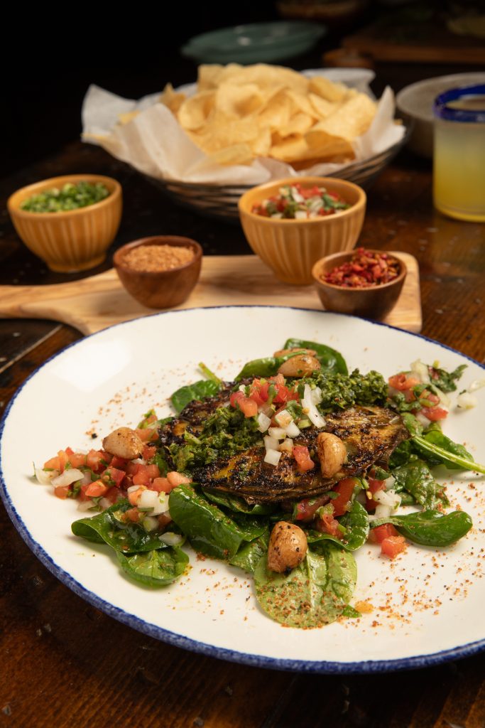 Warm artichoke salad, with spices and chips on wooden table