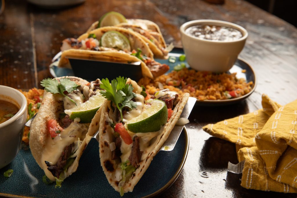 Chicken and Beef Soft Tacos on table with rice and bean sides