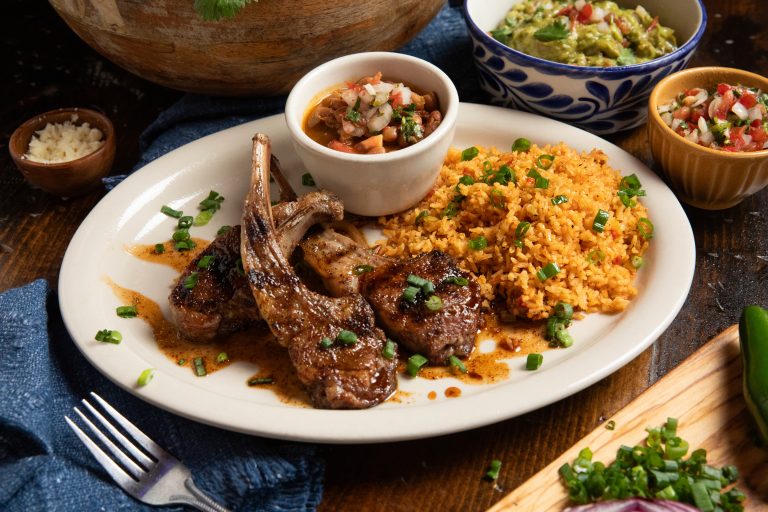 Classic plate of lamb chops with rice and beans. Guacamole in background.