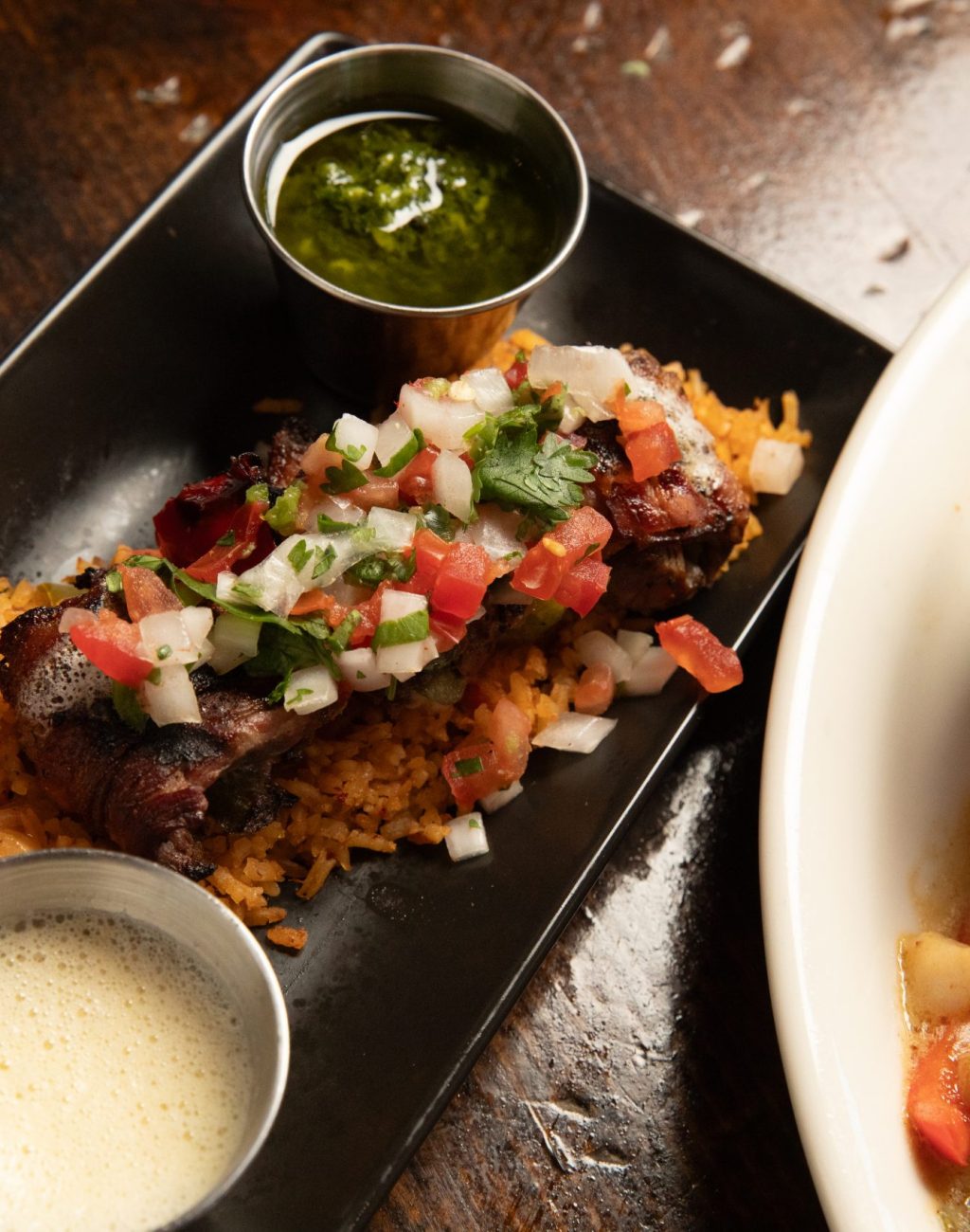 Wooden table with beef brochette and butter together with black beans and salmon.