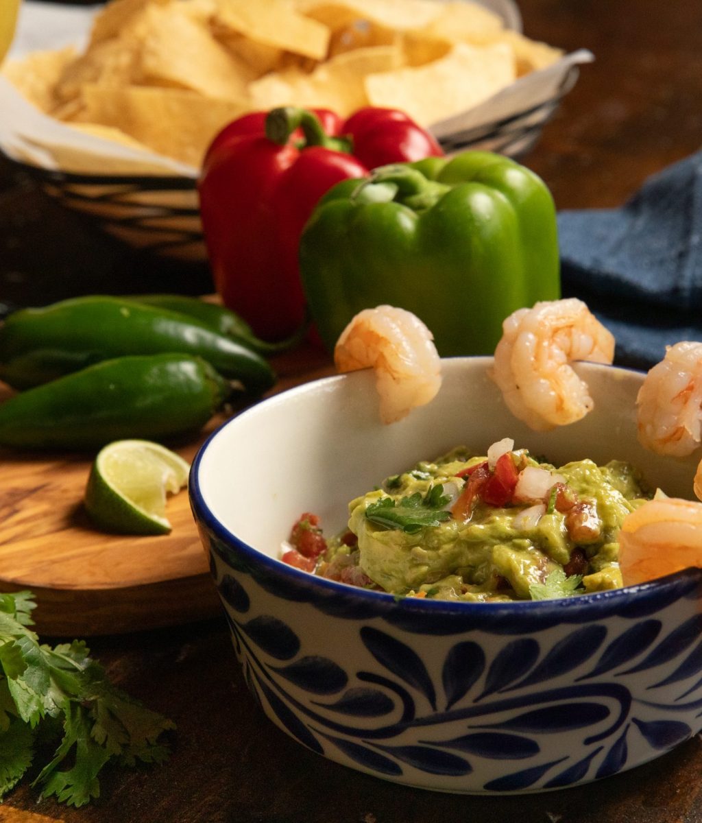 Table set with guacamole and shrimp with jalapeños and peppers. Chips also included.