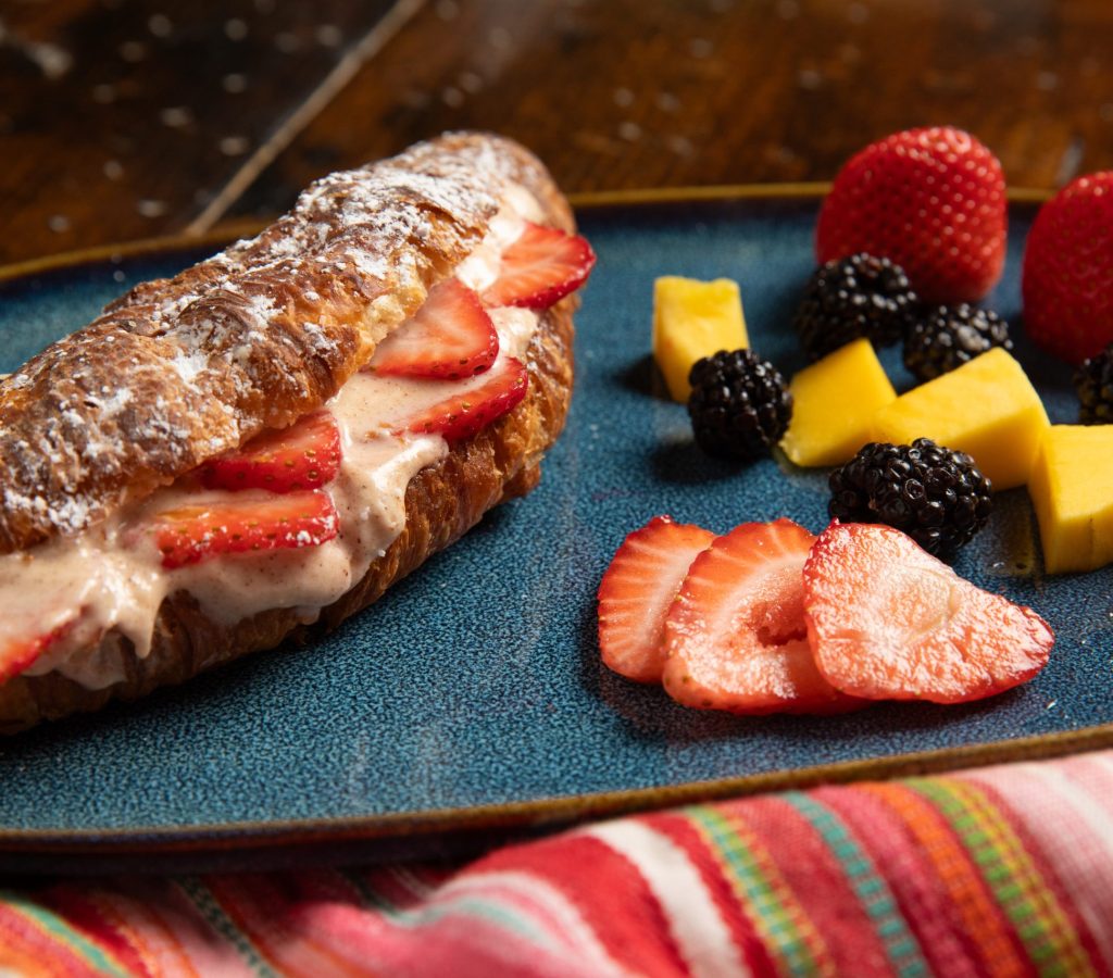 Plate with strawberry croissant and fresh fruit.