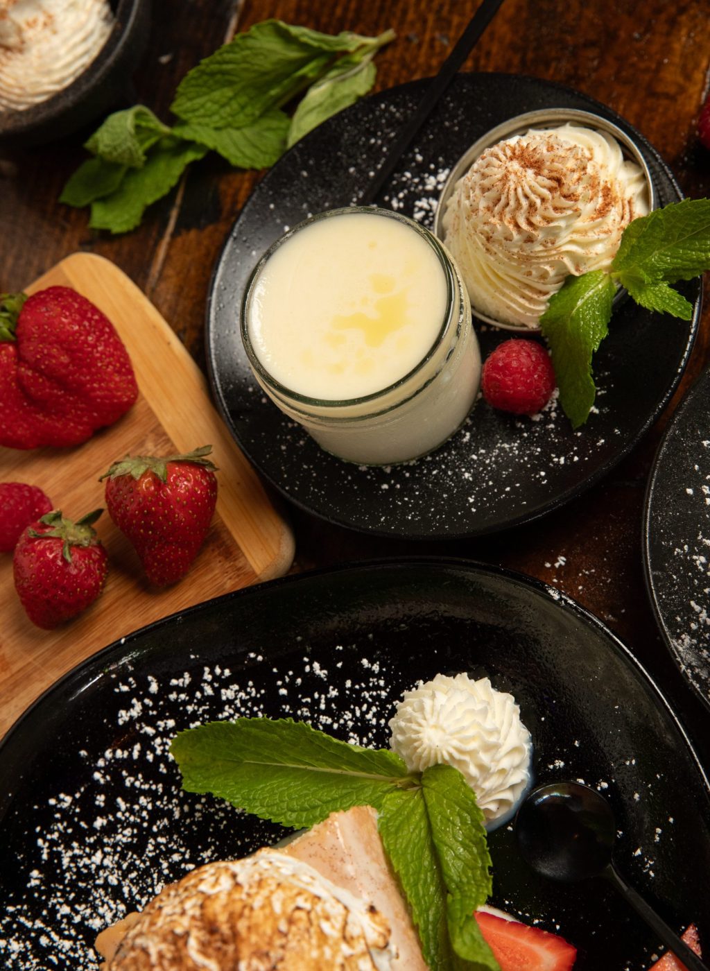 Classic flan on plate with crème and strawberries on the side.