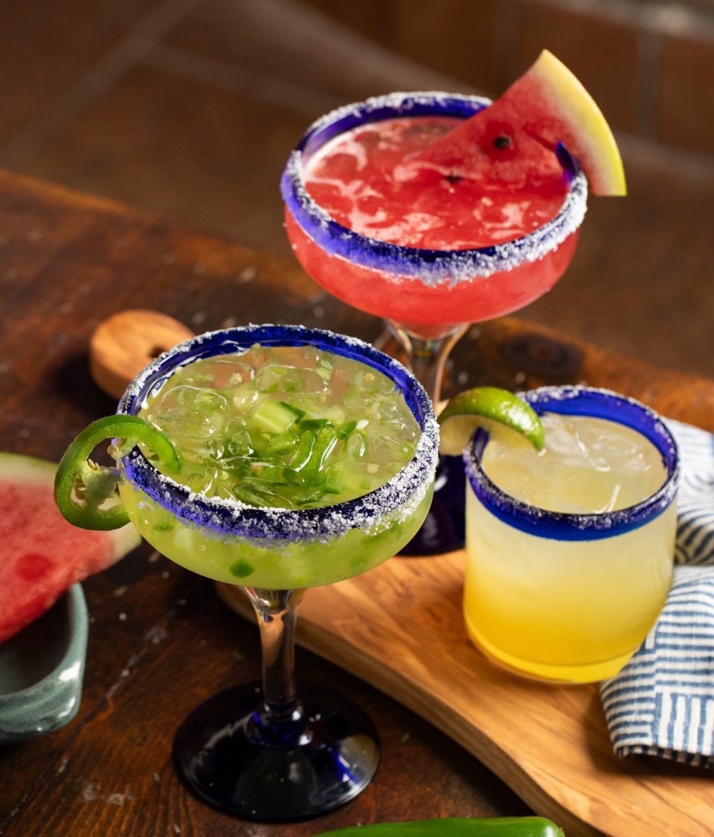 Classic margarita, jalapeno margarita and watermelon table set on wooden table with blue and white stripped napkin.