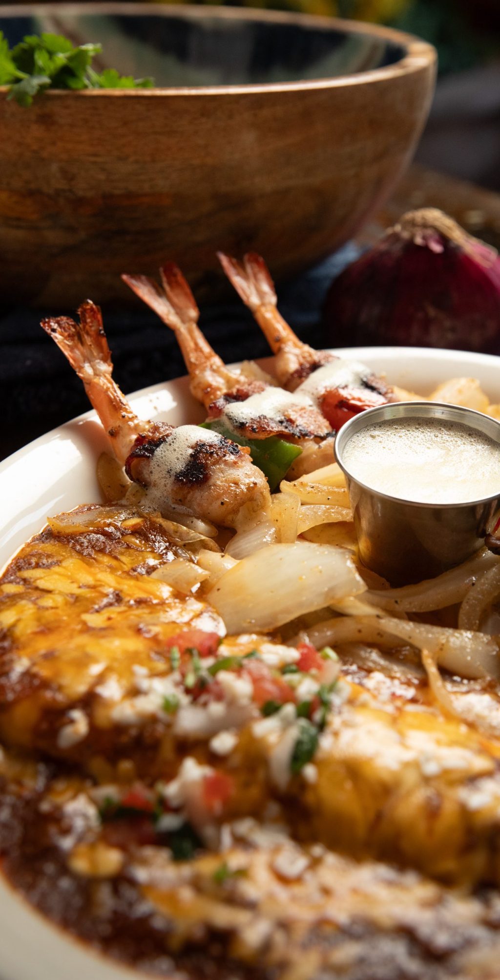 Close up of enchilada plate with grilled shrimp, butter, beans and rice.