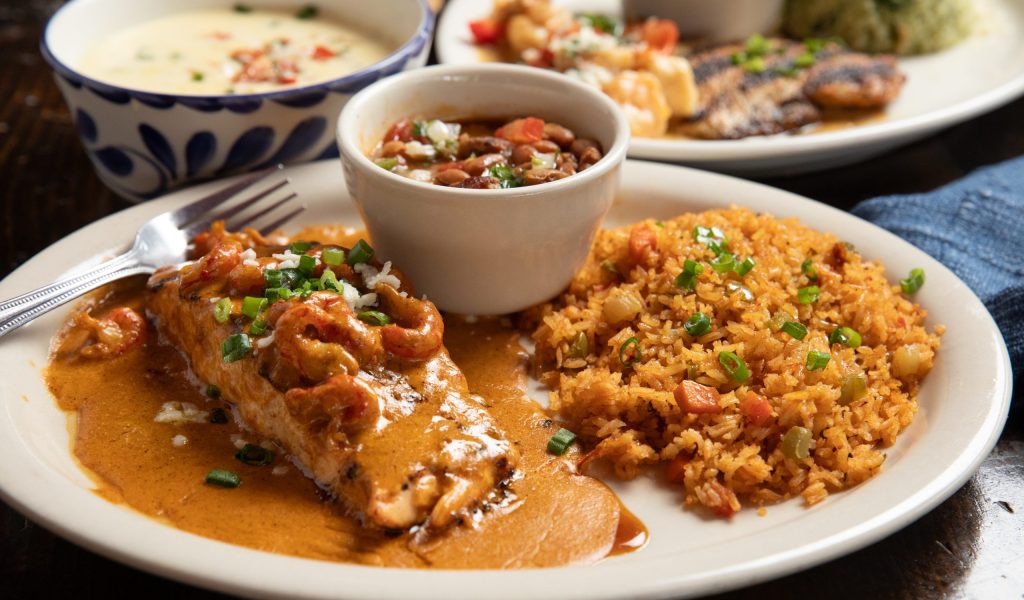 Grilled Salmon on plate with rice and beans. In background queso.