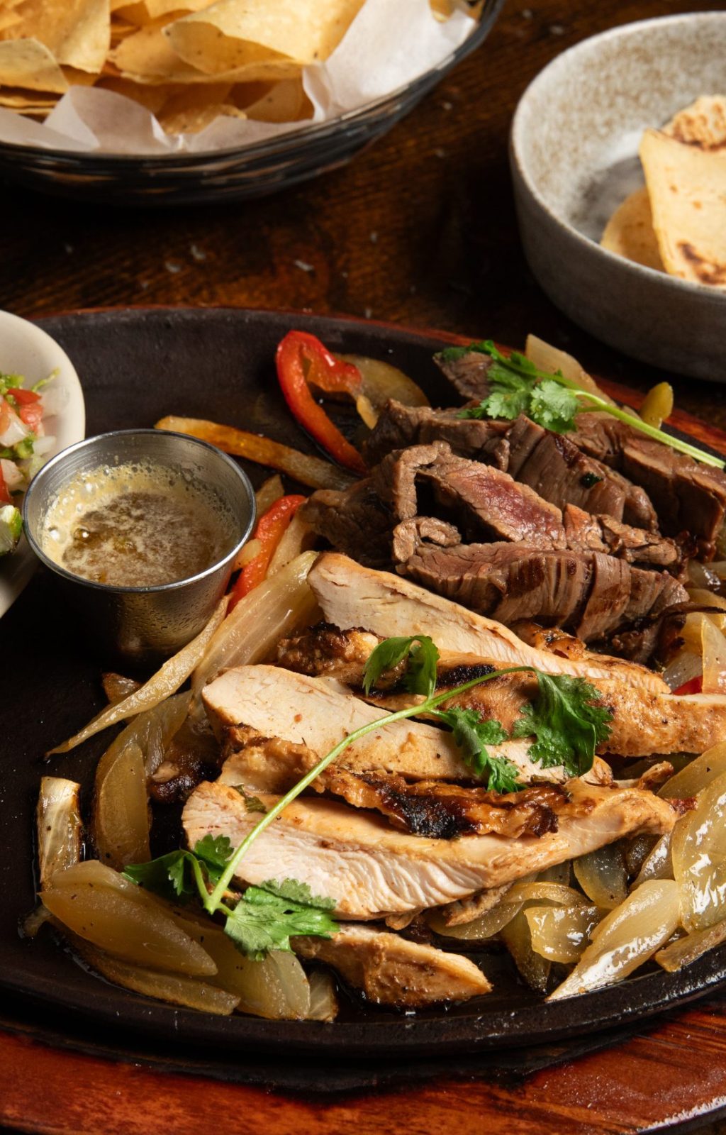 Fajitas on wooden platter, flour tortillas, guacamole