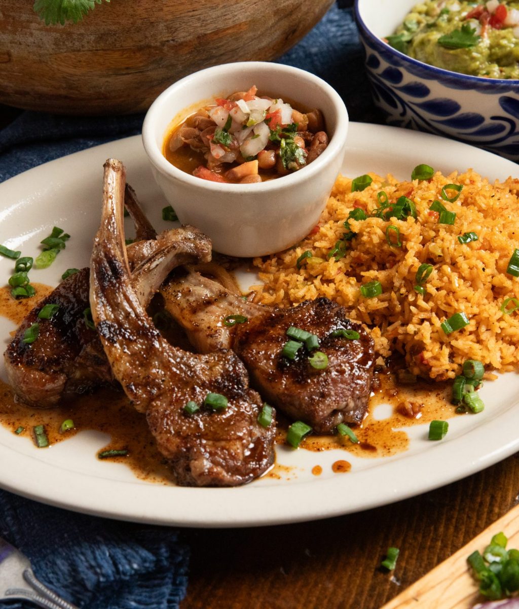 Classic plate of lamb chops with rice and beans. Guacamole in background.