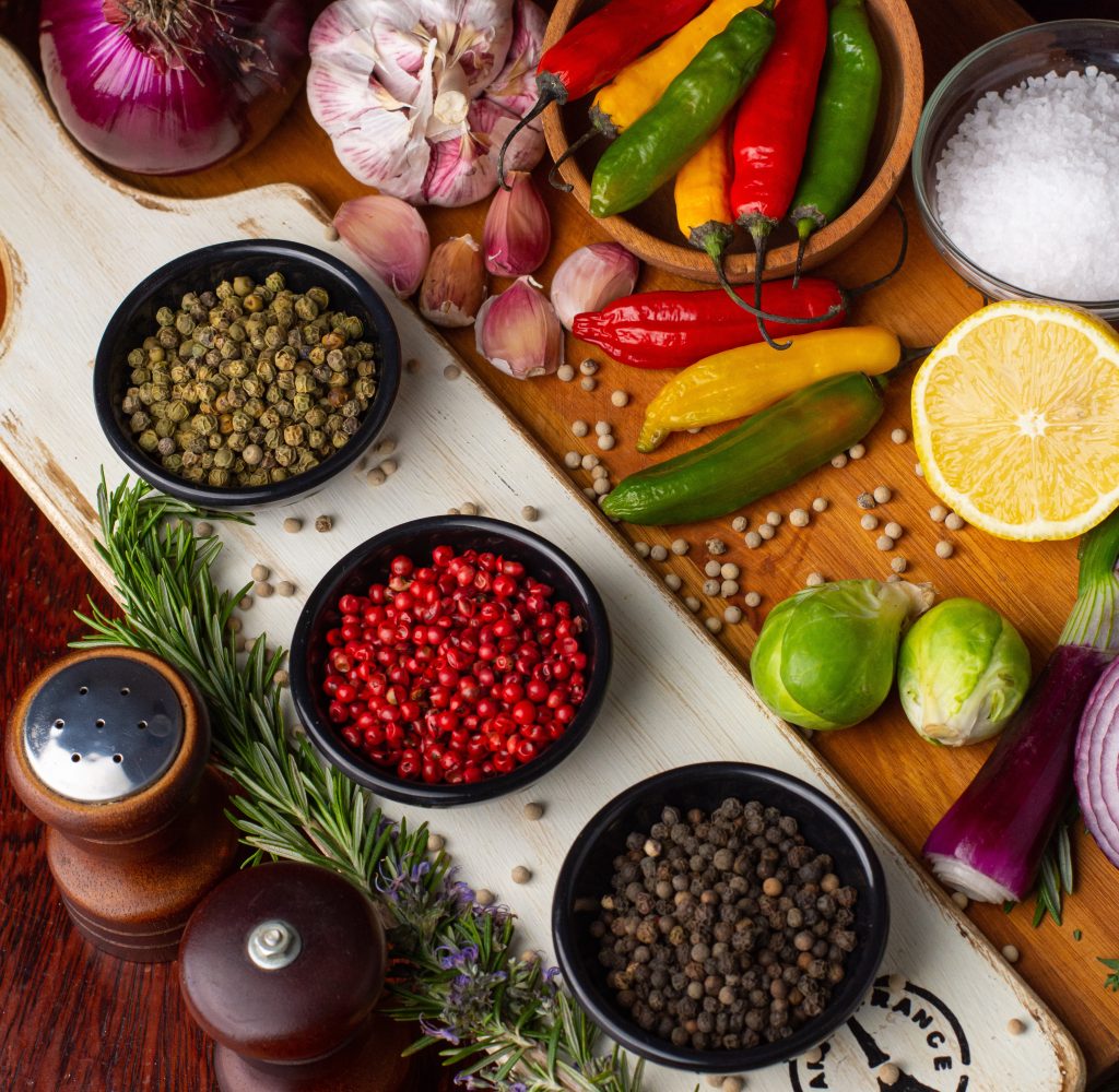 Wooden table holding spices, peppers,limes, onions, salt and pepper